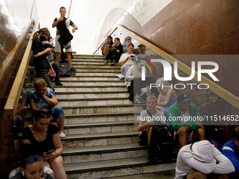 People sit on the steps of an interchange passage at the Teatralna metro station during the massive Russian drone and missile attack on Ukra...