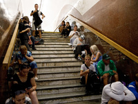 People sit on the steps of an interchange passage at the Teatralna metro station during the massive Russian drone and missile attack on Ukra...