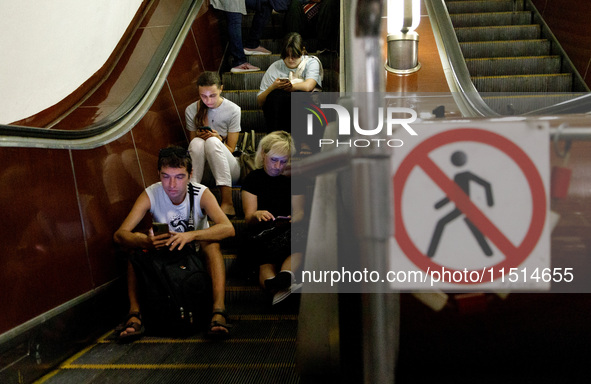 People sit on the steps of an escalator during an air raid alarm at the Teatralna metro station during the massive Russian drone and missile...