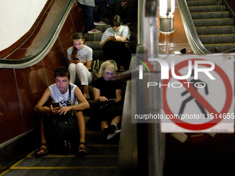 People sit on the steps of an escalator during an air raid alarm at the Teatralna metro station during the massive Russian drone and missile...