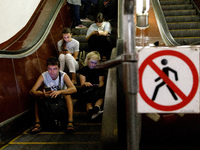 People sit on the steps of an escalator during an air raid alarm at the Teatralna metro station during the massive Russian drone and missile...