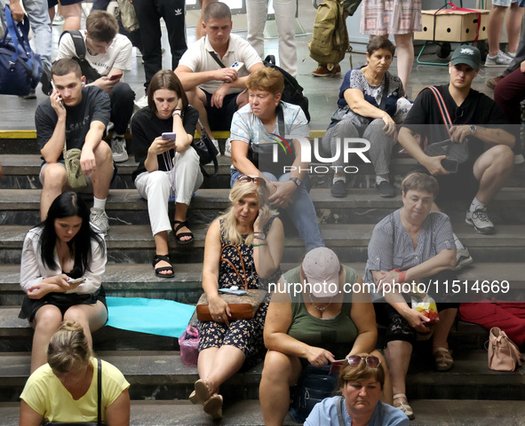 People sit on the steps during an air raid alarm at the Osokorky metro station during the massive Russian drone and missile attack in Kyiv,...