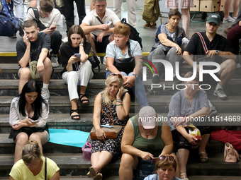 People sit on the steps during an air raid alarm at the Osokorky metro station during the massive Russian drone and missile attack in Kyiv,...