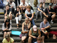 People sit on the steps during an air raid alarm at the Osokorky metro station during the massive Russian drone and missile attack in Kyiv,...