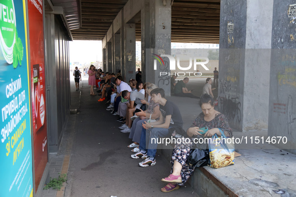 People stand under an overpass during the massive Russian drone and missile attack in Kyiv, Ukraine, on August 26, 2024. NO USE RUSSIA. NO U...