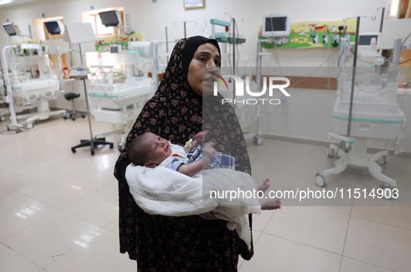 A Palestinian woman prepares to evacuate with her newborn from the Al-Aqsa Martyrs Hospital in Deir al-Balah in the central Gaza Strip on Au...