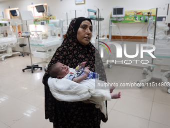 A Palestinian woman prepares to evacuate with her newborn from the Al-Aqsa Martyrs Hospital in Deir al-Balah in the central Gaza Strip on Au...