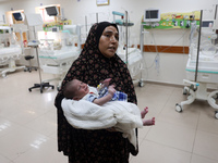 A Palestinian woman prepares to evacuate with her newborn from the Al-Aqsa Martyrs Hospital in Deir al-Balah in the central Gaza Strip on Au...