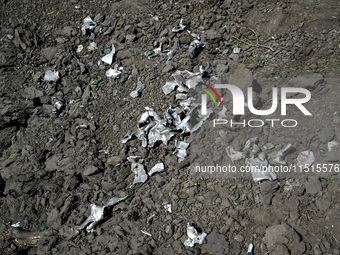 The fragments of a Russian projectile are arranged on the edge of the crater near the house of a man who is killed by the Russian missile at...