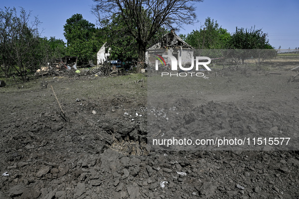 The fragments of a Russian projectile are arranged on the edge of the crater near the house of a man who is killed by the Russian missile at...