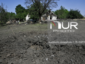 The fragments of a Russian projectile are arranged on the edge of the crater near the house of a man who is killed by the Russian missile at...