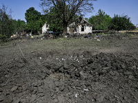 The fragments of a Russian projectile are arranged on the edge of the crater near the house of a man who is killed by the Russian missile at...