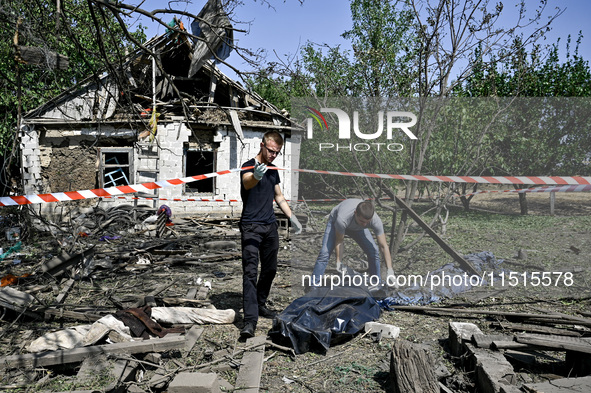 Two men take care of the body of a man in the human remains pouch outside the victim's house after the fatal Russian missile attack in the Z...