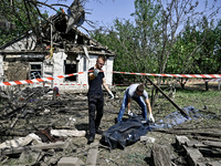 Two men take care of the body of a man in the human remains pouch outside the victim's house after the fatal Russian missile attack in the Z...