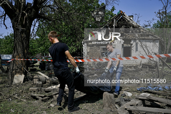 Two men take care of the body of a man in the human remains pouch outside the victim's house after the fatal Russian missile attack in the Z...