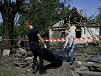 Two men take care of the body of a man in the human remains pouch outside the victim's house after the fatal Russian missile attack in the Z...