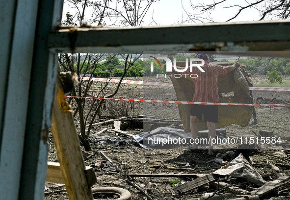 A man covers the body of a man in the human remains pouch with a blanket outside the victim's house after the fatal Russian missile attack i...