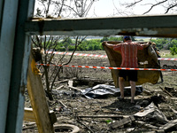 A man covers the body of a man in the human remains pouch with a blanket outside the victim's house after the fatal Russian missile attack i...