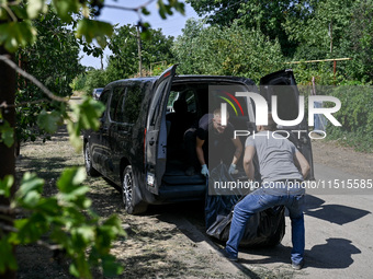 Two men take care of the body of a man in the human remains pouch outside the victim's house after the fatal Russian missile attack in the Z...