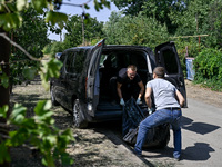 Two men take care of the body of a man in the human remains pouch outside the victim's house after the fatal Russian missile attack in the Z...