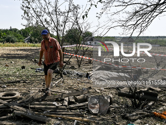 A man walks away from the body in the human remains pouch outside the victim's house after the fatal Russian missile attack in Zaporizhzhia...