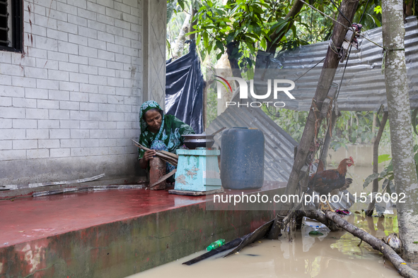 A woman cooks on a separate stove in front of her house due to floods in the Aburhat area of Mirsarai Upazila of Chittagong Division, Bangla...