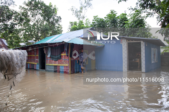 A female member walks in front of a flooded house in the Aburhat area of Mirsarai Upazila of Chittagong Division, Bangladesh, on August 26,...