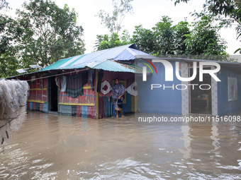 A female member walks in front of a flooded house in the Aburhat area of Mirsarai Upazila of Chittagong Division, Bangladesh, on August 26,...