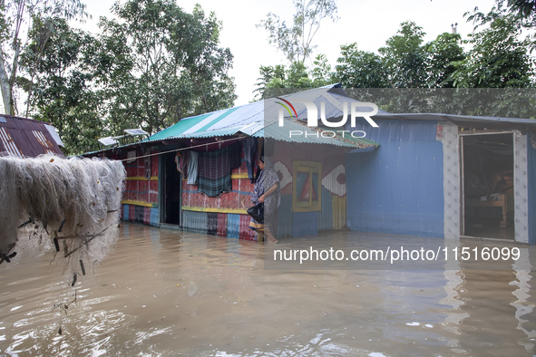 A female member walks in front of a flooded house in the Aburhat area of Mirsarai Upazila of Chittagong Division, Bangladesh, on August 26,...