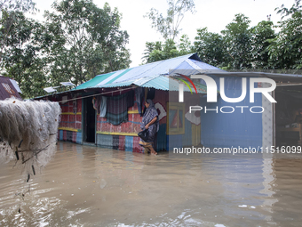 A female member walks in front of a flooded house in the Aburhat area of Mirsarai Upazila of Chittagong Division, Bangladesh, on August 26,...