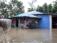 A female member walks in front of a flooded house in the Aburhat area of Mirsarai Upazila of Chittagong Division, Bangladesh, on August 26,...