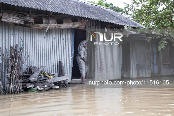 A woman washes her feet in flood water in front of her house in the Aburhat area of Mirsarai Upazila in Chittagong Division, Bangladesh, on...