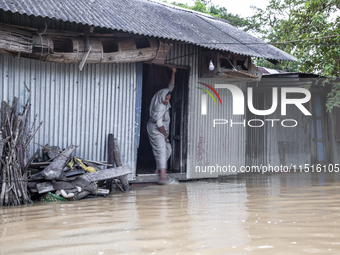 A woman washes her feet in flood water in front of her house in the Aburhat area of Mirsarai Upazila in Chittagong Division, Bangladesh, on...