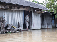 A woman washes her feet in flood water in front of her house in the Aburhat area of Mirsarai Upazila in Chittagong Division, Bangladesh, on...