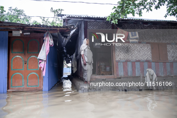 A woman stands in front of her flooded house in the Aburhat area of Mirsarai Upazila in Chittagong Division, Bangladesh, on August 26, 2024....