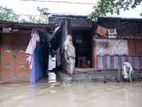 A woman stands in front of her flooded house in the Aburhat area of Mirsarai Upazila in Chittagong Division, Bangladesh, on August 26, 2024....