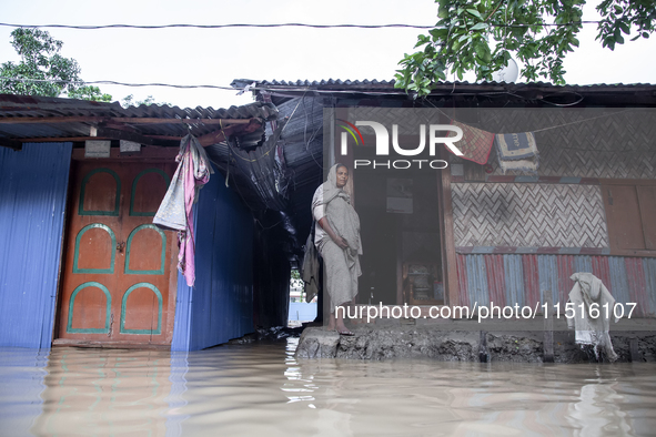 A woman stands in front of her flooded house in the Aburhat area of Mirsarai Upazila in Chittagong Division, Bangladesh, on August 26, 2024....