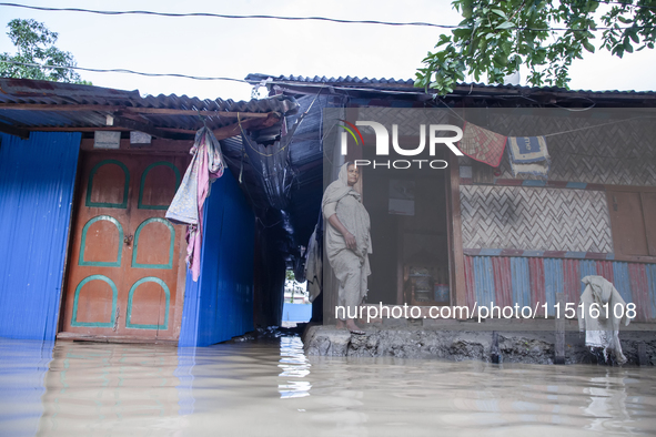 A woman stands in front of her flooded house in the Aburhat area of Mirsarai Upazila in Chittagong Division, Bangladesh, on August 26, 2024....