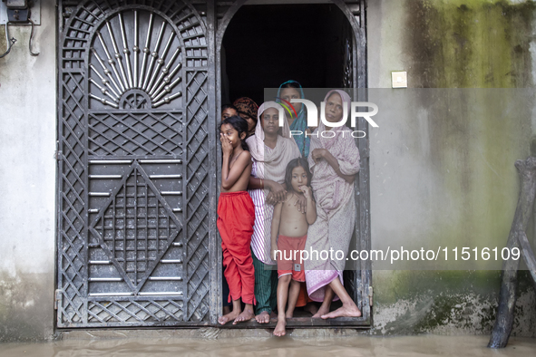 On August 26, 2024, in Mirsarai, Chittagong, Bangladesh, some female members of a family stand at the front gate of their flooded house in t...