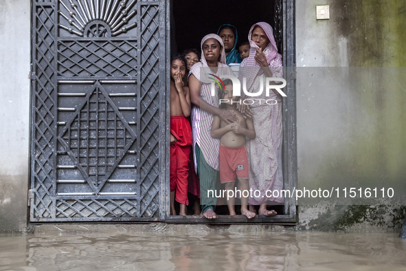 On August 26, 2024, in Mirsarai, Chittagong, Bangladesh, some female members of a family stand at the front gate of their flooded house in t...