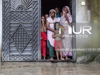 On August 26, 2024, in Mirsarai, Chittagong, Bangladesh, some female members of a family stand at the front gate of their flooded house in t...