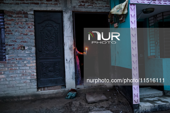 A woman of a family stands in the middle of her flood-damaged house with candles lit in the Aburhat area of Mirsarai Upazila of Chittagong D...