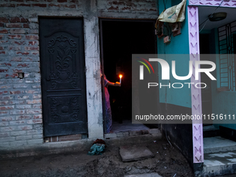 A woman of a family stands in the middle of her flood-damaged house with candles lit in the Aburhat area of Mirsarai Upazila of Chittagong D...