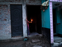 A woman of a family stands in the middle of her flood-damaged house with candles lit in the Aburhat area of Mirsarai Upazila of Chittagong D...