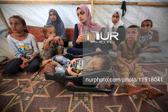 Palestinian infant Abdul Rahman Abu Al-Jidyan, 11, who contracts polio, receives care from his mother and family inside a tent in a shelter...