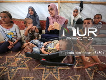 Palestinian infant Abdul Rahman Abu Al-Jidyan, 11, who contracts polio, receives care from his mother and family inside a tent in a shelter...