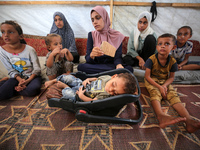 Palestinian infant Abdul Rahman Abu Al-Jidyan, 11, who contracts polio, receives care from his mother and family inside a tent in a shelter...