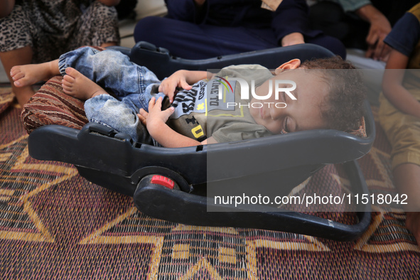 Palestinian infant Abdul Rahman Abu Al-Jidyan, 11, who contracts polio, receives care from his mother and family inside a tent in a shelter...