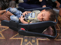 Palestinian infant Abdul Rahman Abu Al-Jidyan, 11, who contracts polio, receives care from his mother and family inside a tent in a shelter...