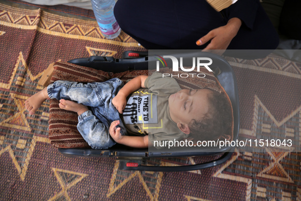 Palestinian infant Abdul Rahman Abu Al-Jidyan, 11, who contracts polio, receives care from his mother and family inside a tent in a shelter...